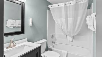 A bathroom with a white sink, a toilet, and a shower with a white curtain.