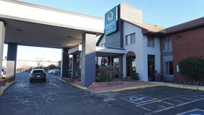 A Quality Inn by Choice Hotels with a covered parking area, a brick building, and a sign indicating a handicapped parking space. - Quality Inn near Potomac Mills (Woodbridge)