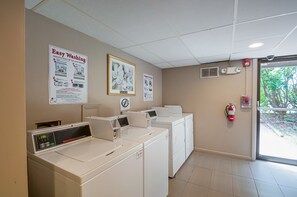 A laundry facility with multiple washing machines, a fire extinguisher, and informational posters on the walls. - Quality Inn near Potomac Mills (Woodbridge)