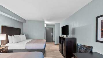 Habitación de hotel con dos camas, televisión, escritorio y una silla.