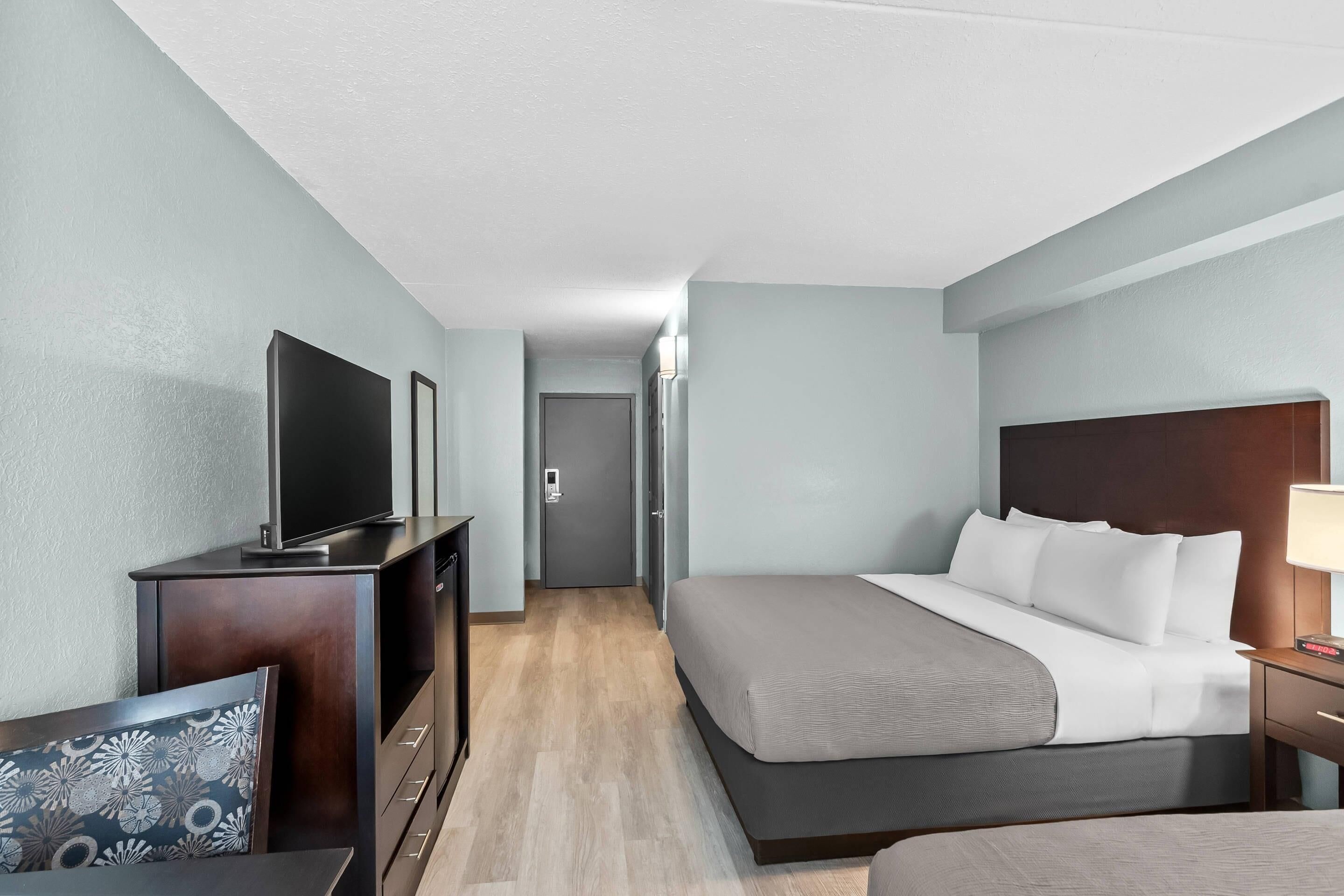 A hotel room with a bed, a TV, a desk, and a chair.