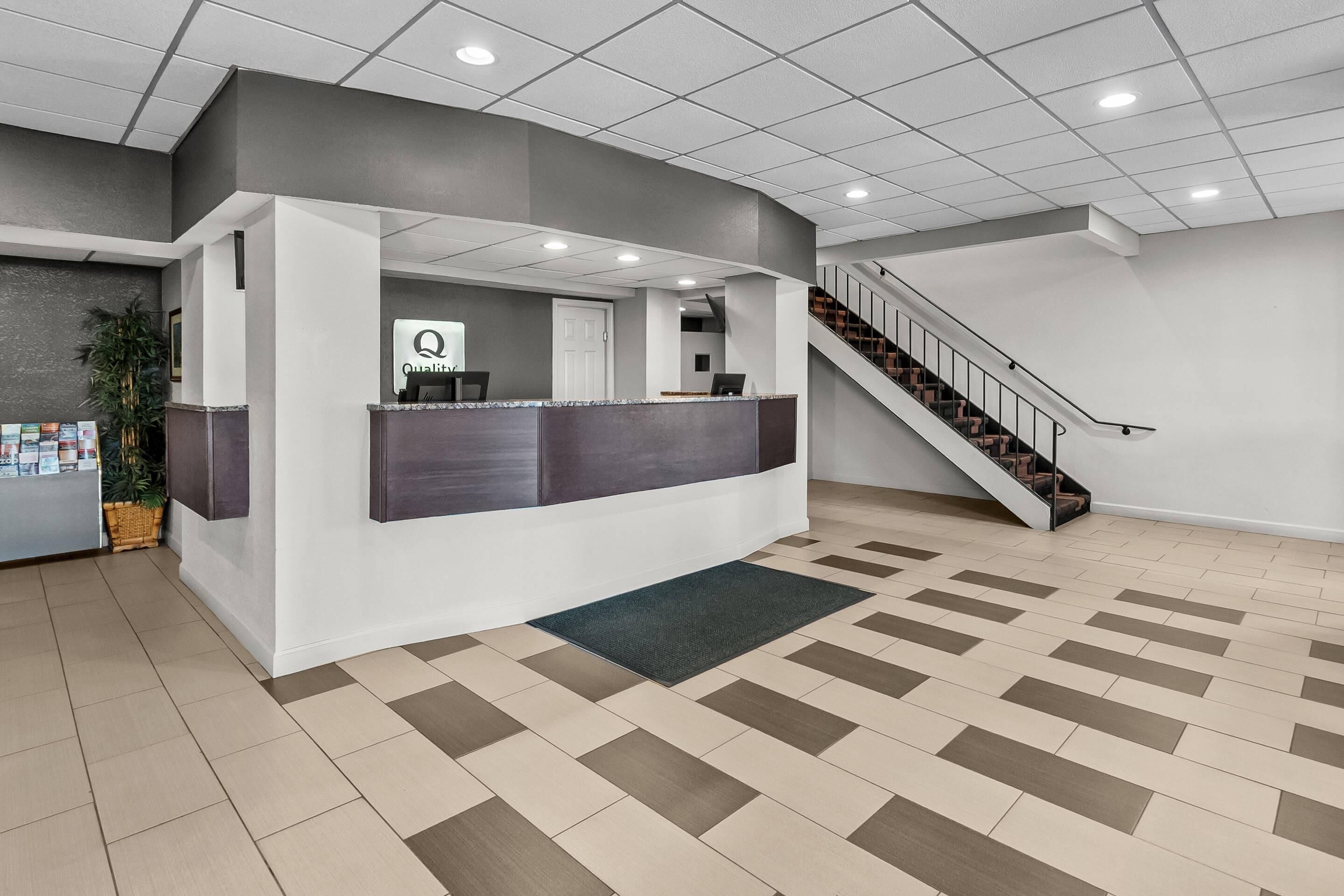Zona de recepción con mostrador, escalera y piso estampado.