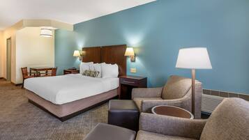 A hotel room with a large bed, a desk, a chair, and a sofa.