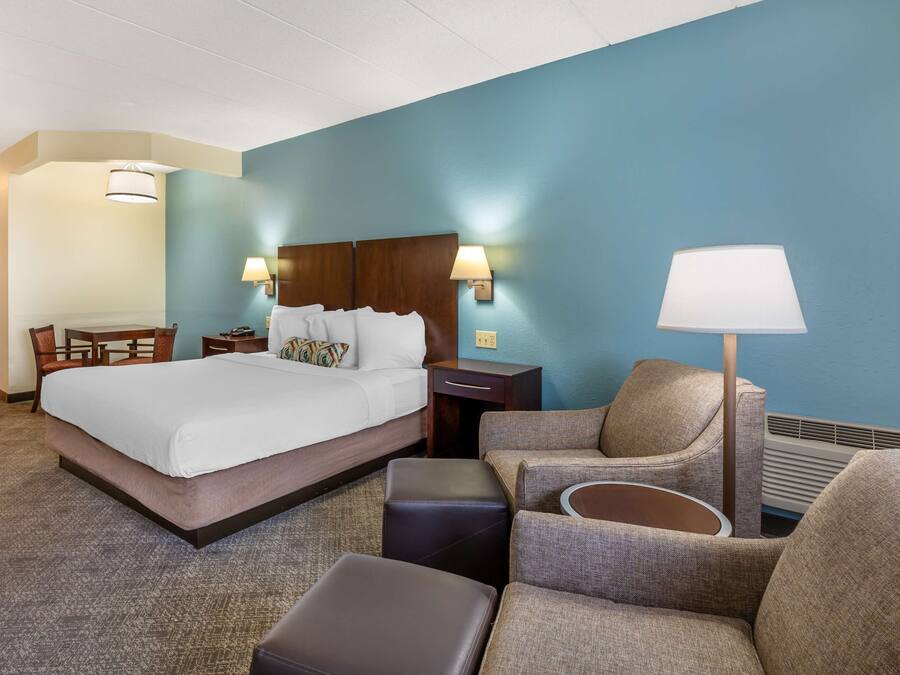A hotel room with a large bed, a desk, a chair, and a sofa.