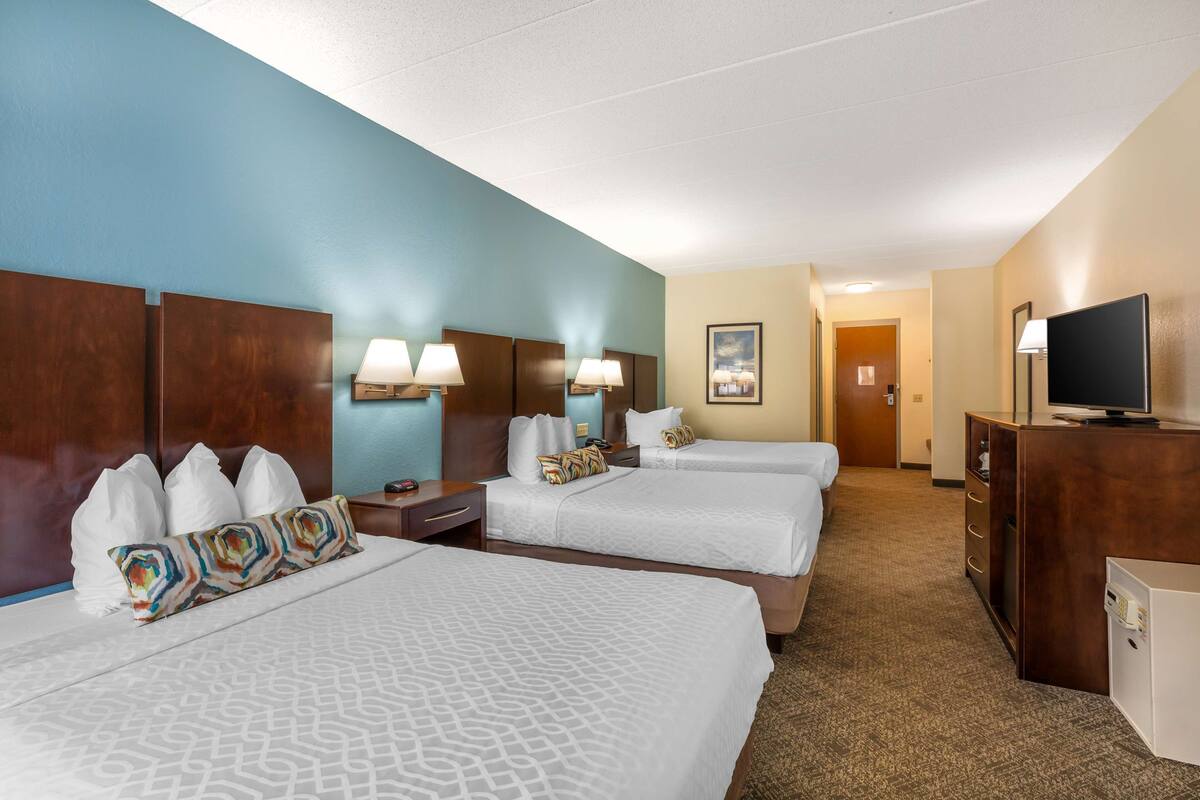 A hotel room with two beds, a TV, a desk, and a bathroom.