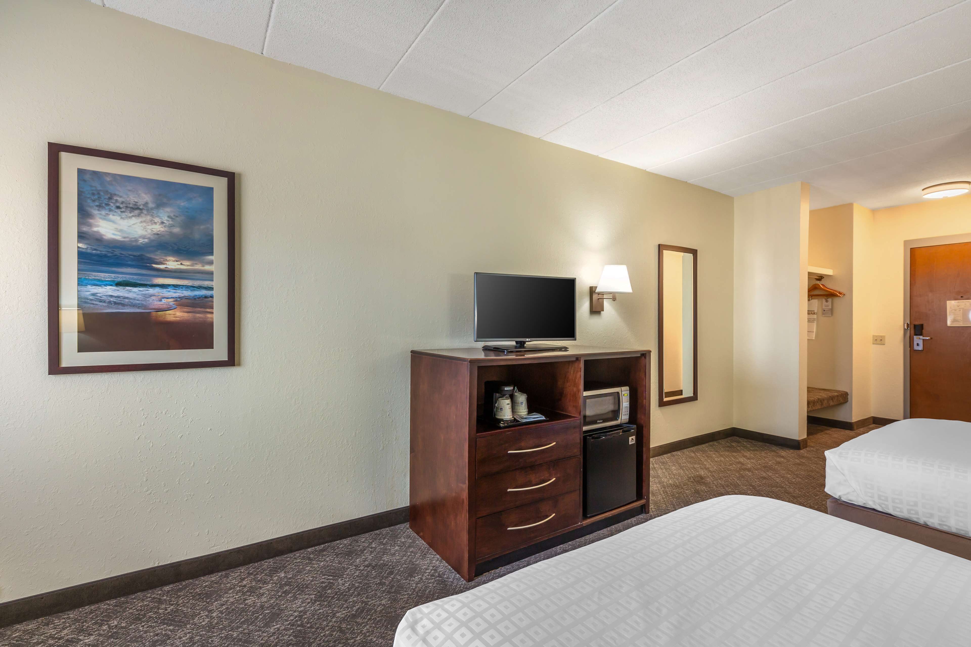 A hotel room with two beds, a television, a microwave, and a small refrigerator.
