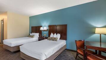 A hotel room with two beds, a desk, and a chair.