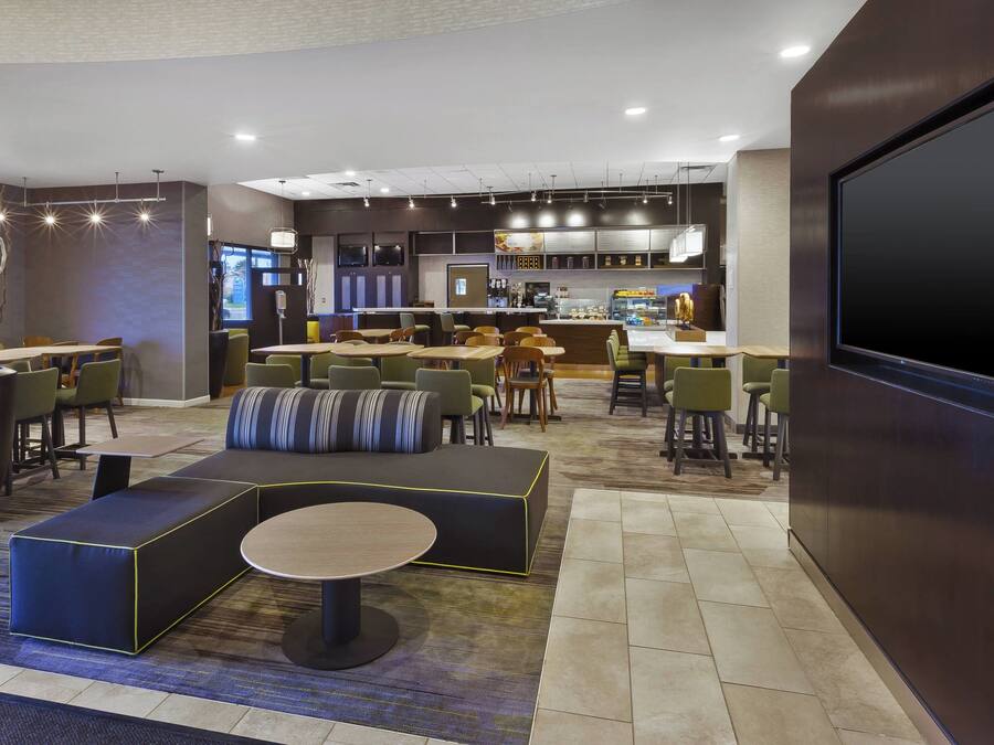 Un moderno vestíbulo de hotel con una zona de estar, un bar y una cocina al fondo.