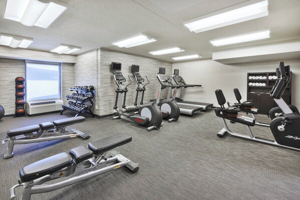 A gym with treadmills, elliptical machines, and weight benches.