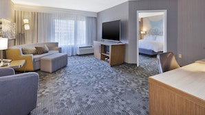 Una habitación de hotel con sofá, televisión, escritorio y cama.