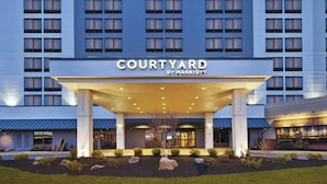 Un hotel Courtyard by Marriott con fachada moderna, múltiples ventanas y una entrada bien iluminada.