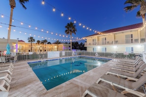 Una piscina al aire libre, sombrillas, sillones reclinables de piscina