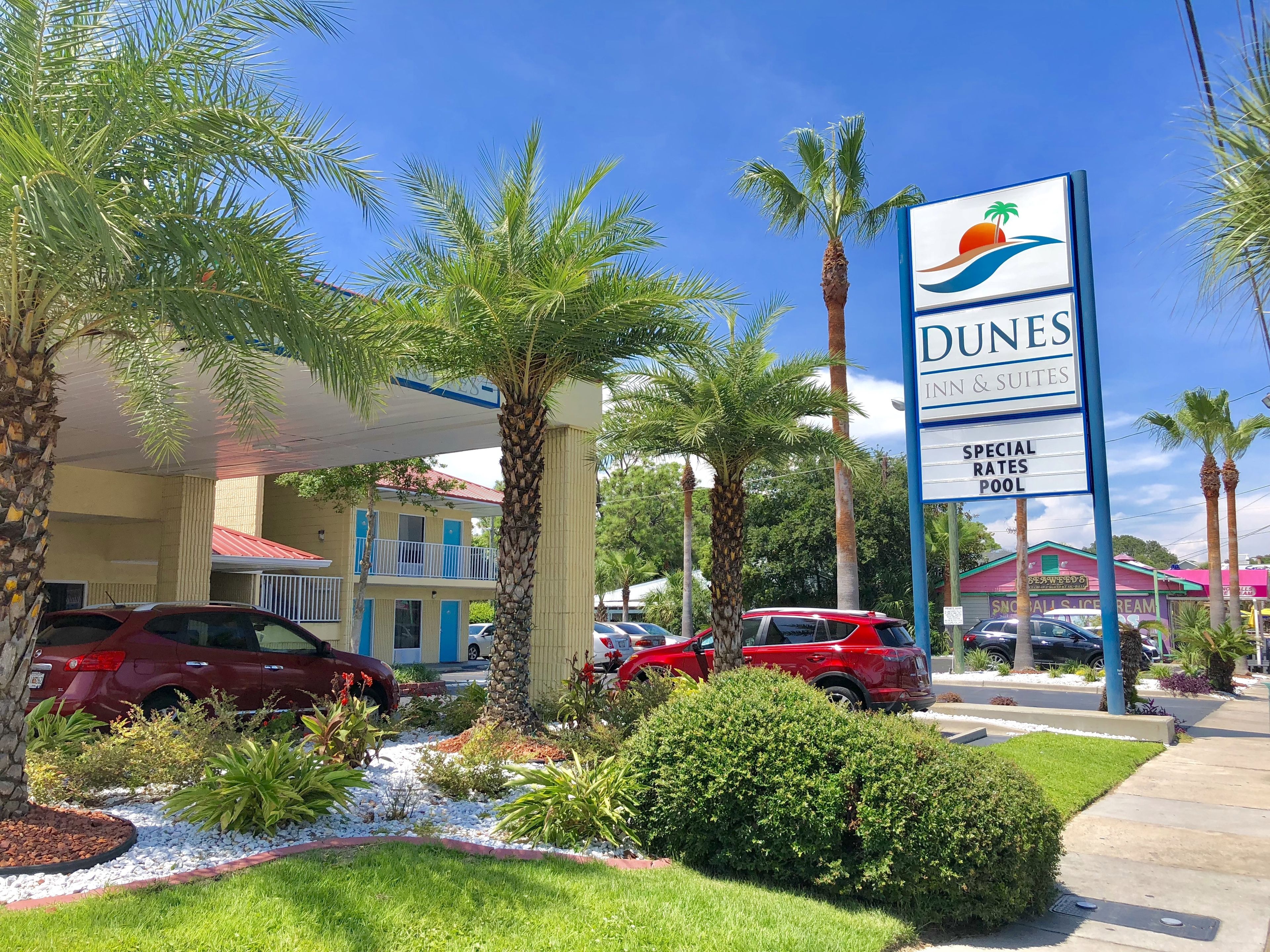 Ett hotell som heter Dunes Inn & Suites, med en skylt som annonserar specialpriser och en pool.