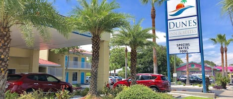 Ett hotell som heter Dunes Inn & Suites, med en skylt som annonserar specialpriser och en pool.