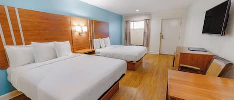 Una habitación de hotel con dos camas, un escritorio, una silla, un televisor y una ventana con cortinas.