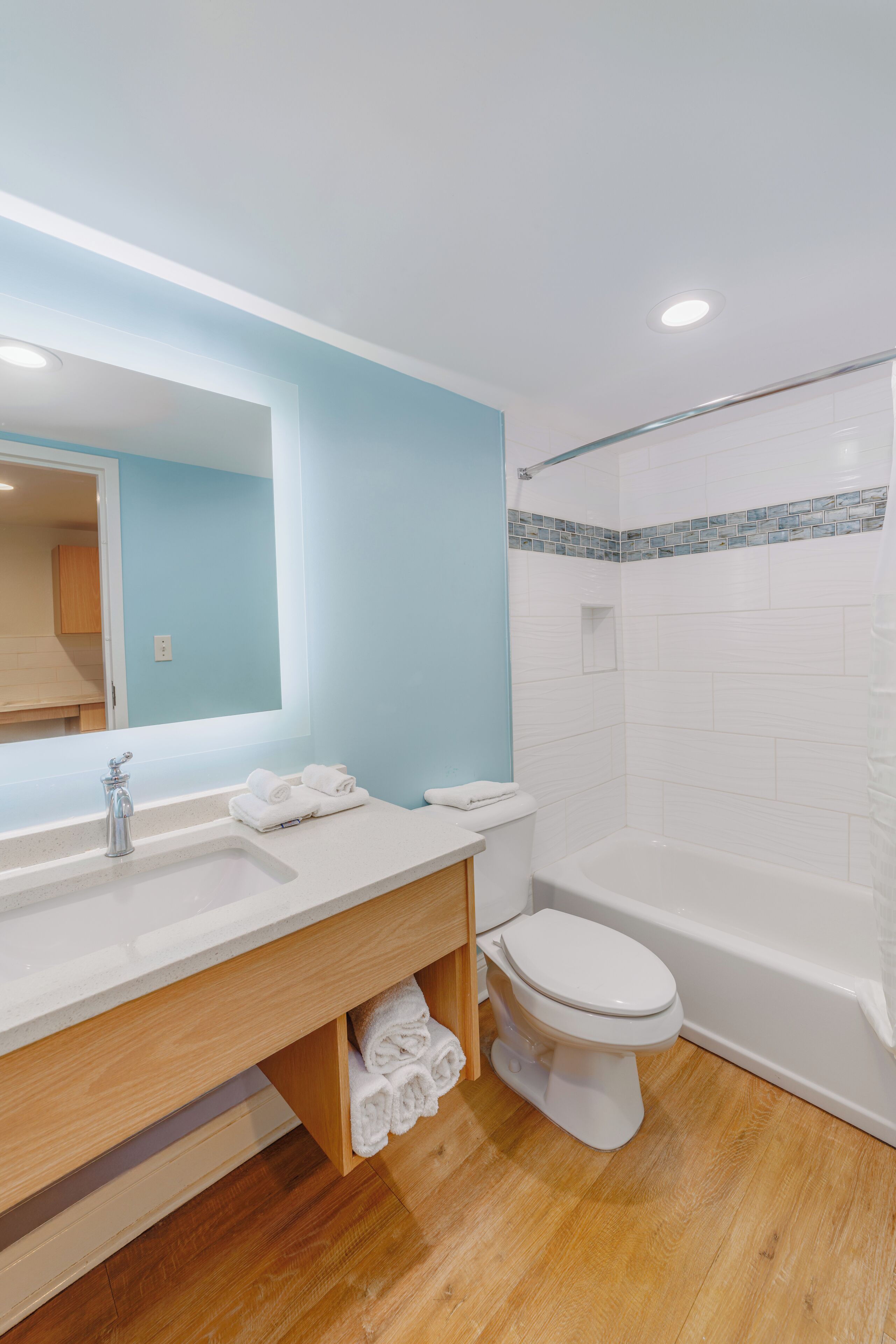 Un bany modern amb un tocador de fusta, un lavabo blanc i una banyera.