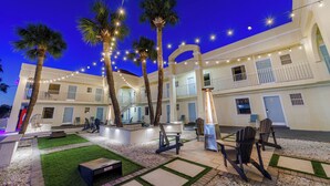 A hotel courtyard with palm trees, string lights, outdoor seating, and a well-maintained lawn. - Dunes Inn & Suites (Tybee Island)
