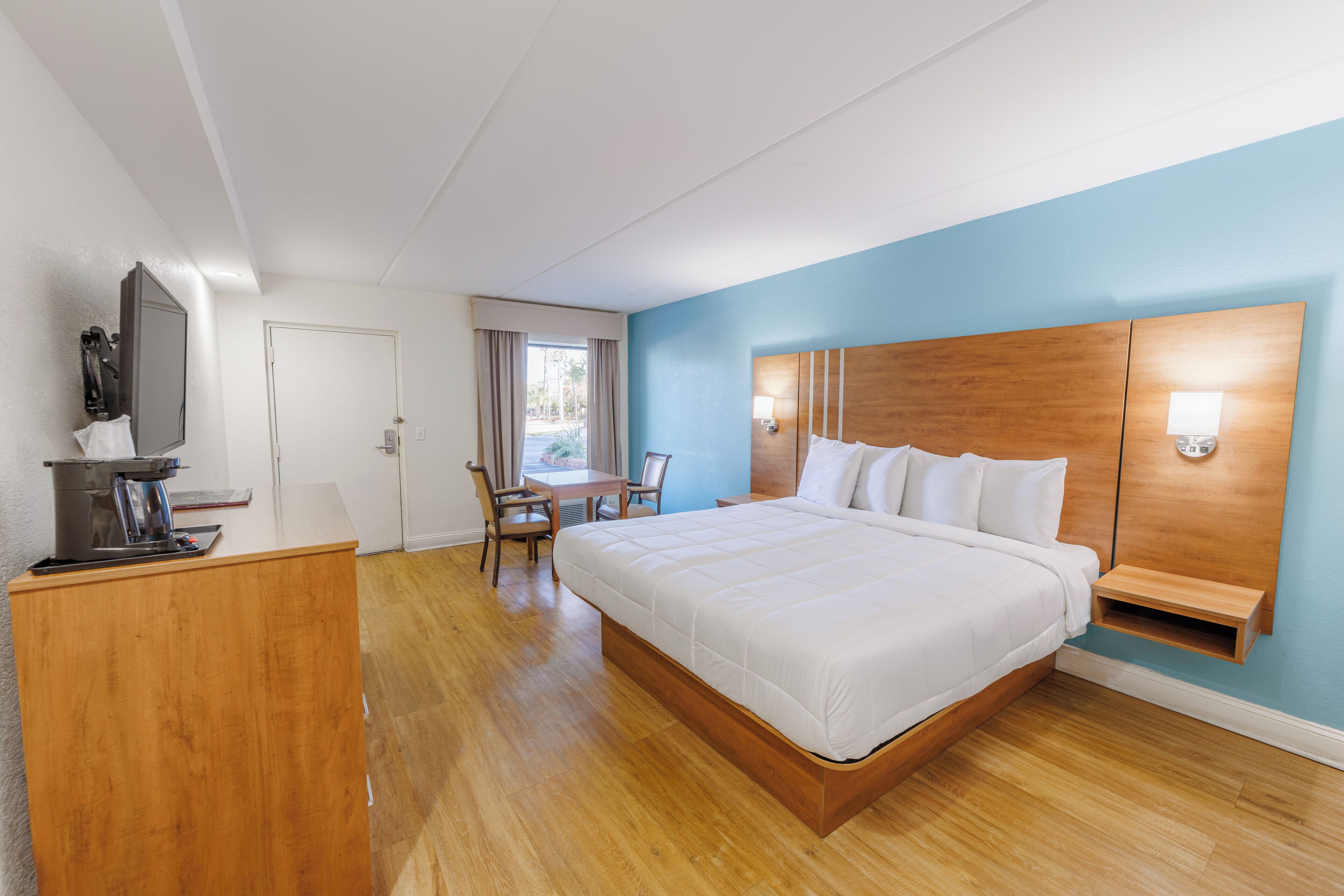 A hotel room with a large bed, a desk, and a chair.