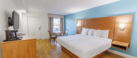 A hotel room with a large bed, a desk, and a chair.