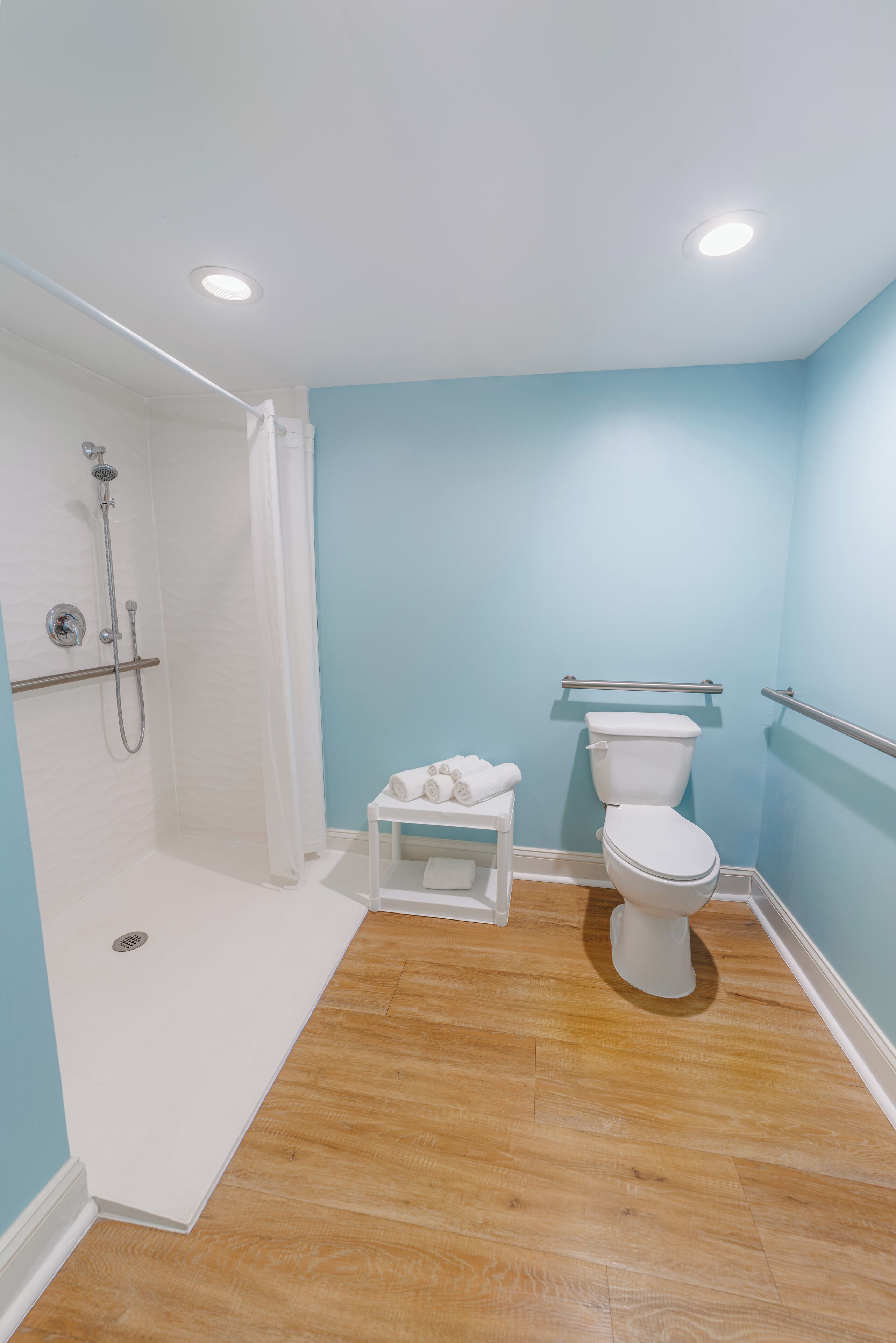 Ein Badezimmer mit Dusche, Toilette und einem kleinen Tisch mit Handtüchern.