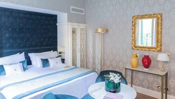 Une chambre d’hôtel avec un grand lit, une table de chevet avec une lampe, un miroir et des vases décoratifs.