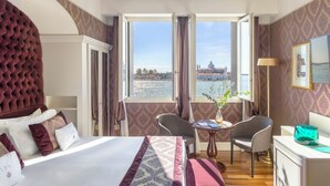 Quarto de hotel com uma cama grande, uma escrivaninha e vista para o horizonte urbano pela janela.