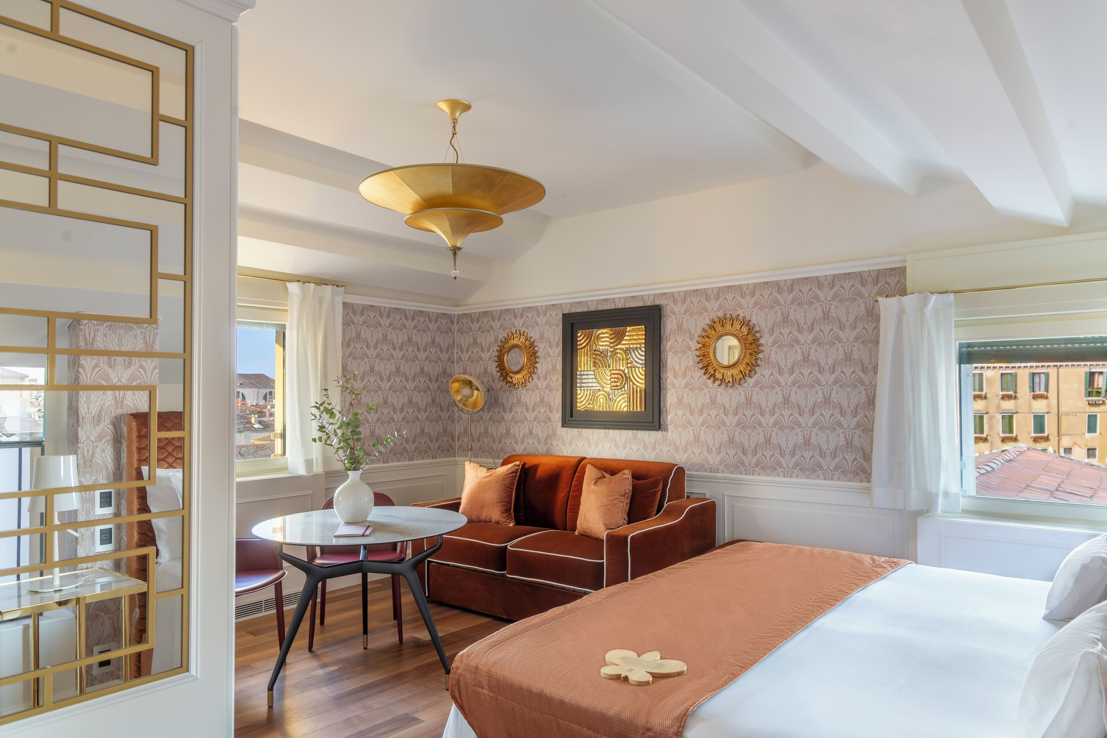 Ein Hotelzimmer mit Bett, einer Couch, einem Esstisch und Blick auf die Stadt durch das Fenster.