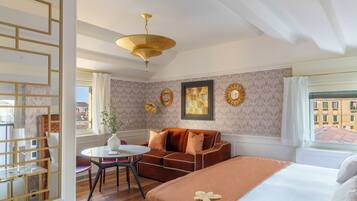 Ein Hotelzimmer mit Bett, einer Couch, einem Esstisch und Blick auf die Stadt durch das Fenster.