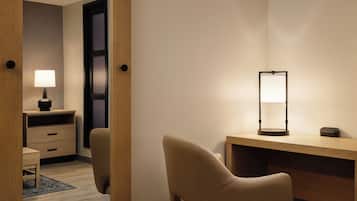 Une chambre d’hôtel avec un bureau en bois, une chaise, une lampe et une armoire.
