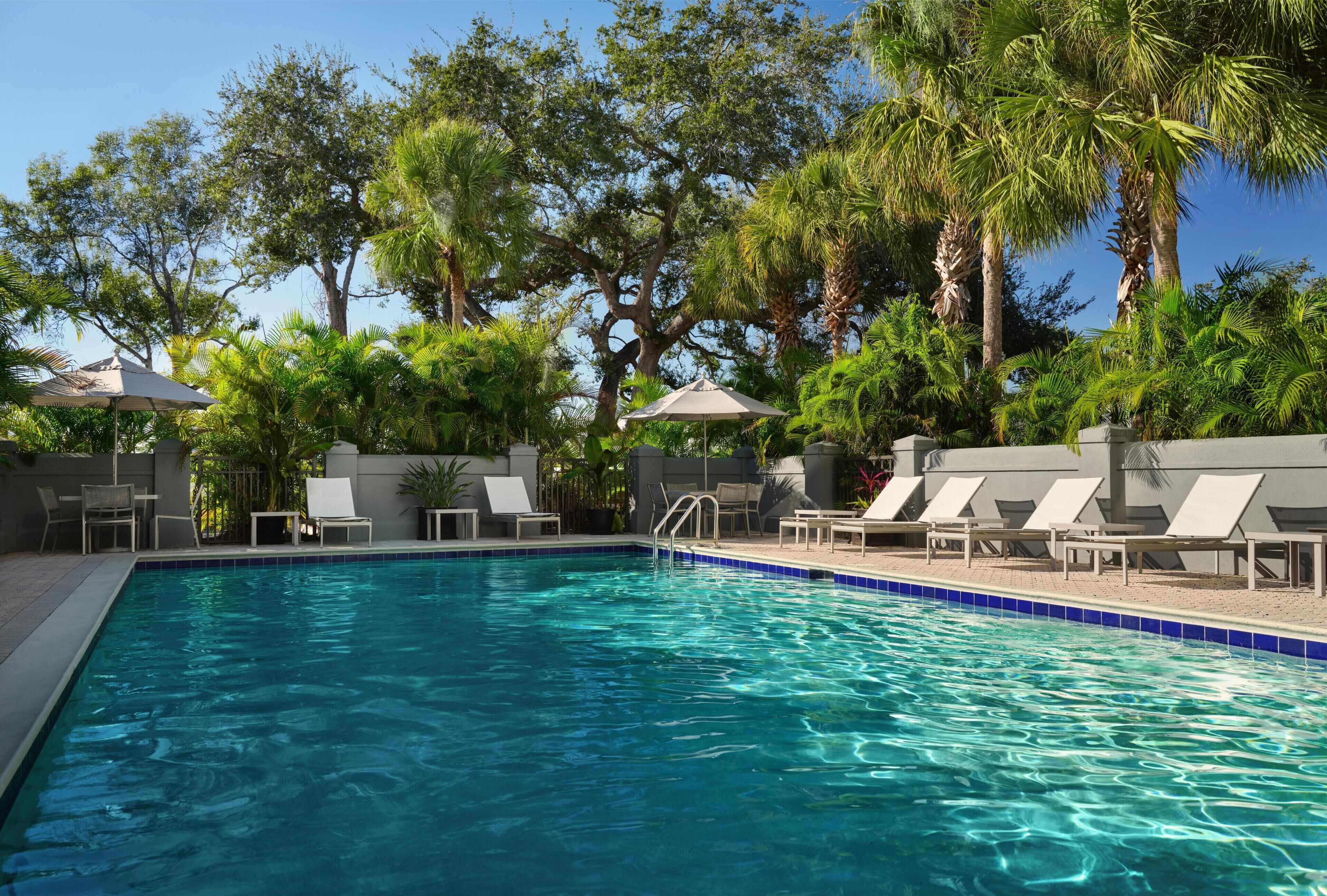 Una piscina al aire libre, sillones reclinables de piscina