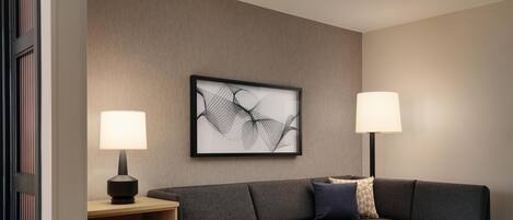 Una sala de estar moderna con un sofá modular, una mesita auxiliar, una lámpara y una obra de arte abstracta enmarcada en la pared.