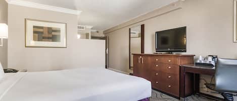 Quarto de hotel com cama, escrivaninha, televisão e cómoda.