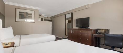 Una habitación de hotel con dos camas, televisión, escritorio con silla y cómoda.