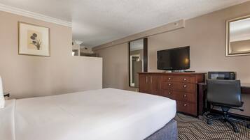 A hotel room with a bed, a desk with a chair, a TV, and a microwave.