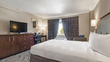 A hotel room with a bed, a TV, a desk, and a chair.