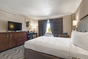 A hotel room with a bed, a TV, a desk, and a chair.
