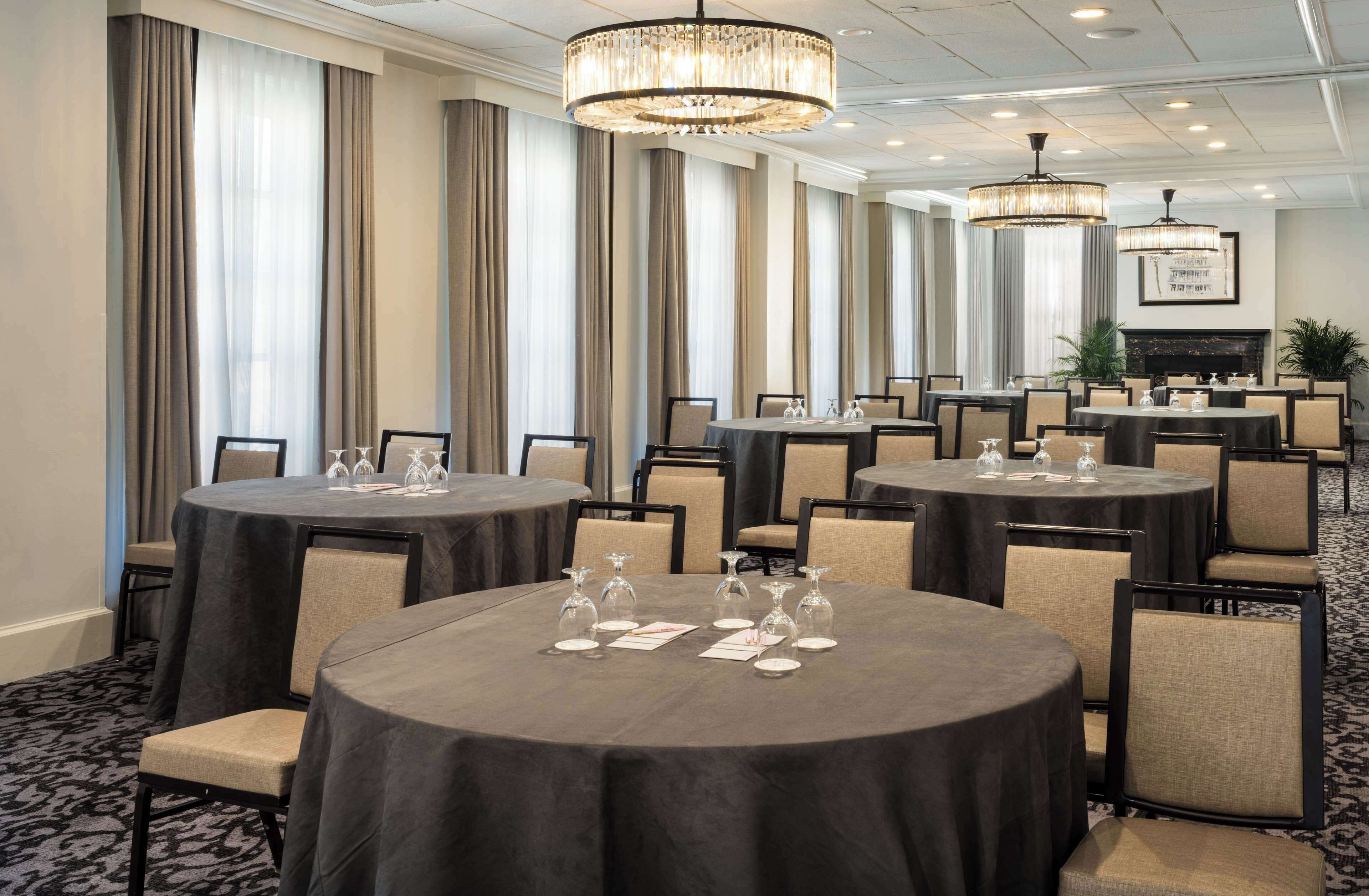 A conference room with round tables, chairs, and chandeliers.