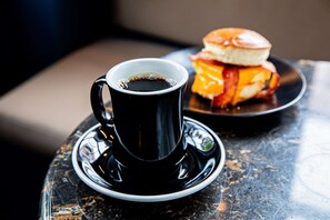 Eine Tasse Kaffee auf einem Untertasse und ein Burger auf einem Teller auf einem Tisch.