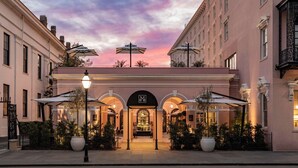 A hotel entrance with a covered patio, arched passageway, and outdoor seating area. - Mills House Charleston, Curio Collection by Hilton (Charleston)