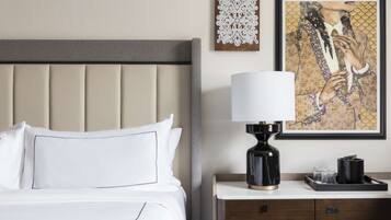 Habitación de hotel con cama, mesita de noche, lámpara y dos cuadros en la pared.