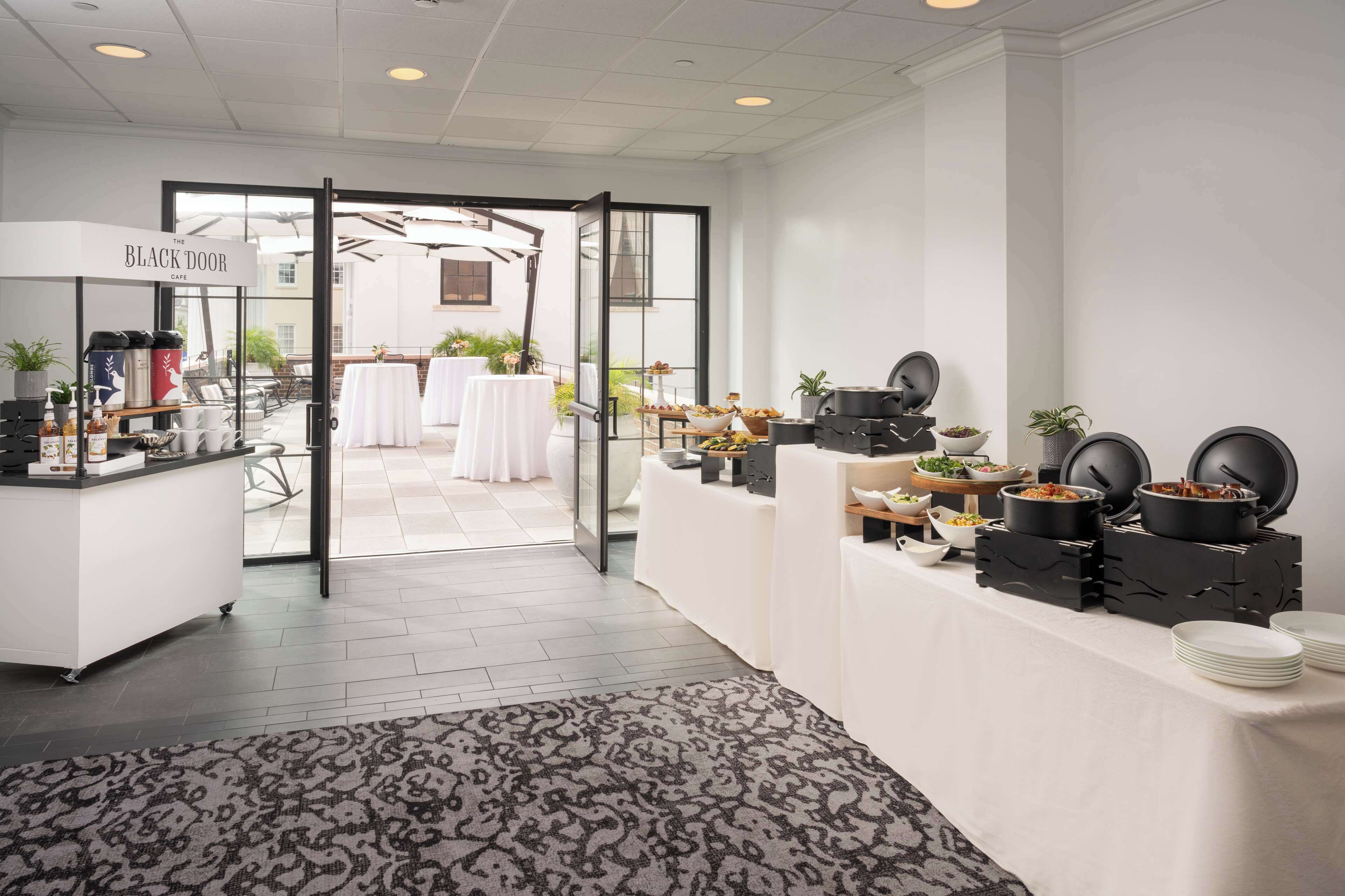 Un hall d’hôtel moderne comprenant un comptoir d’accueil, un espace café et un buffet.