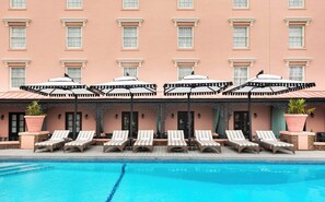A hotel with a pool area, featuring lounge chairs and umbrellas.