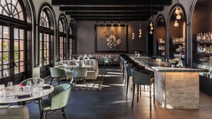 A modern bar area with a marble countertop, multiple seating arrangements, and a large decorative wall piece. - Mills House Charleston, Curio Collection by Hilton (Charleston)