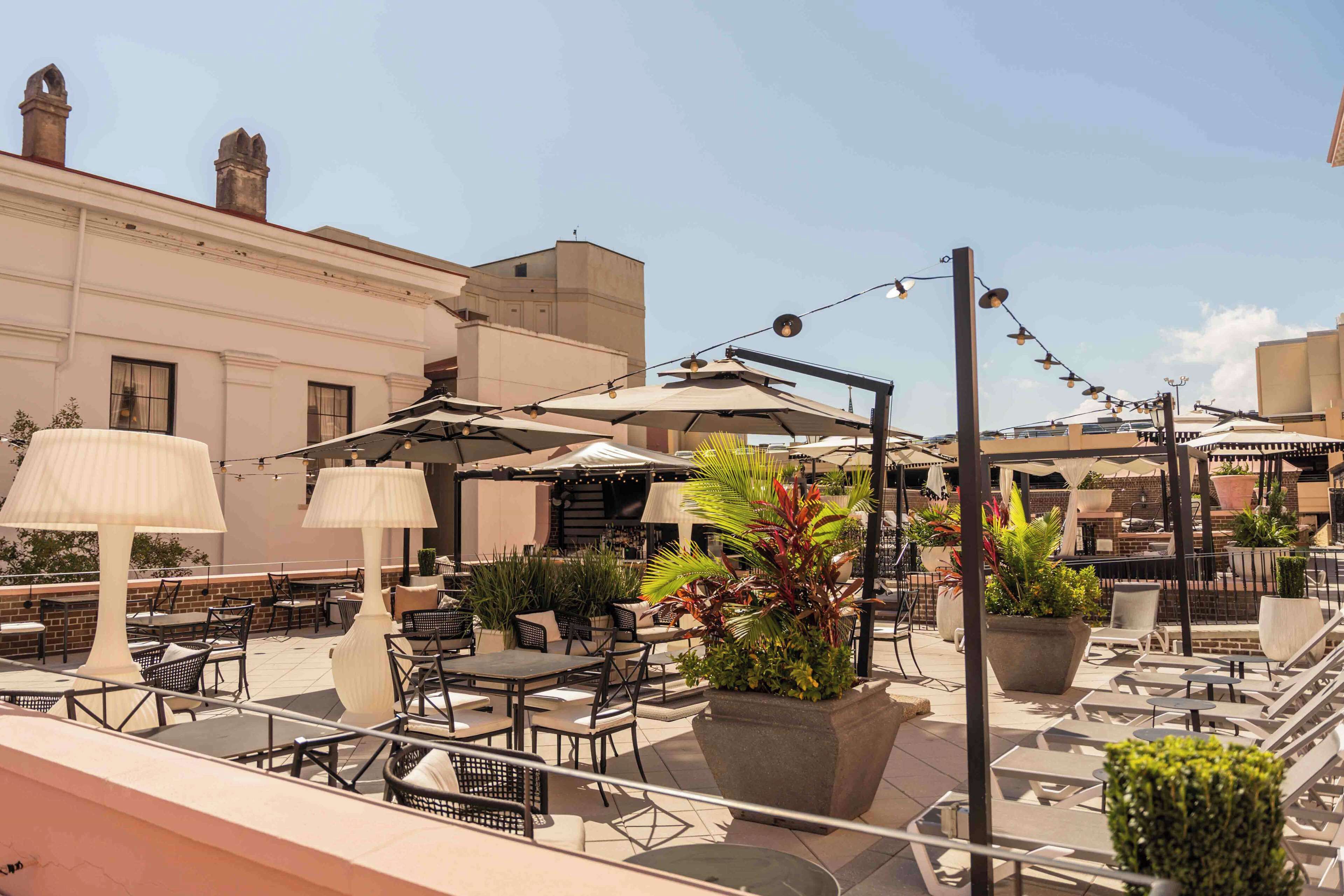 Una terrazza sul tetto con posti a sedere all'aperto, ombrelloni e piante in vaso.