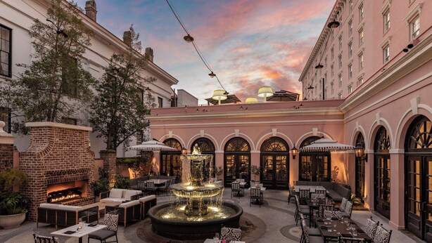An outdoor patio with a brick fireplace, a fountain, and seating areas. - Mills House Charleston, Curio Collection by Hilton (Charleston)