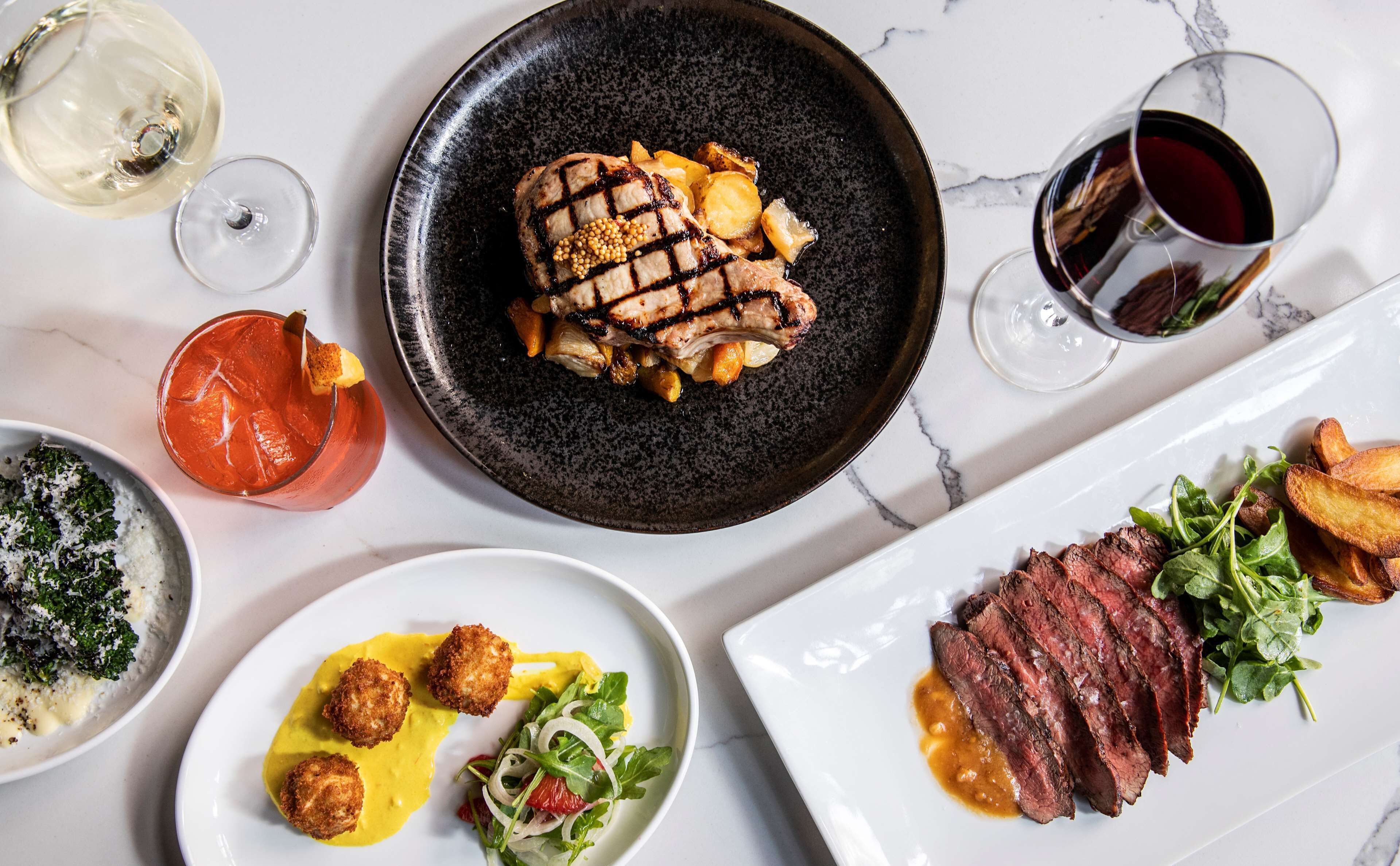 Un assortiment de plats comprenant de la viande grillée, des pommes de terre rôties et une salade, servis sur une table en marbre.