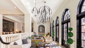 A spacious lobby with a white sofa, a wooden coffee table, and a chandelier. - Mills House Charleston, Curio Collection by Hilton (Charleston)