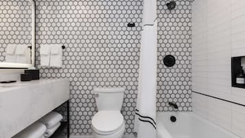 A bathroom with a hexagonal tile pattern, a toilet, a sink with a mirror, and a bathtub.