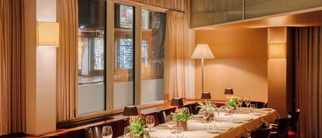 A conference room with a long table set for a meeting, large windows with curtains, and a carpeted floor.