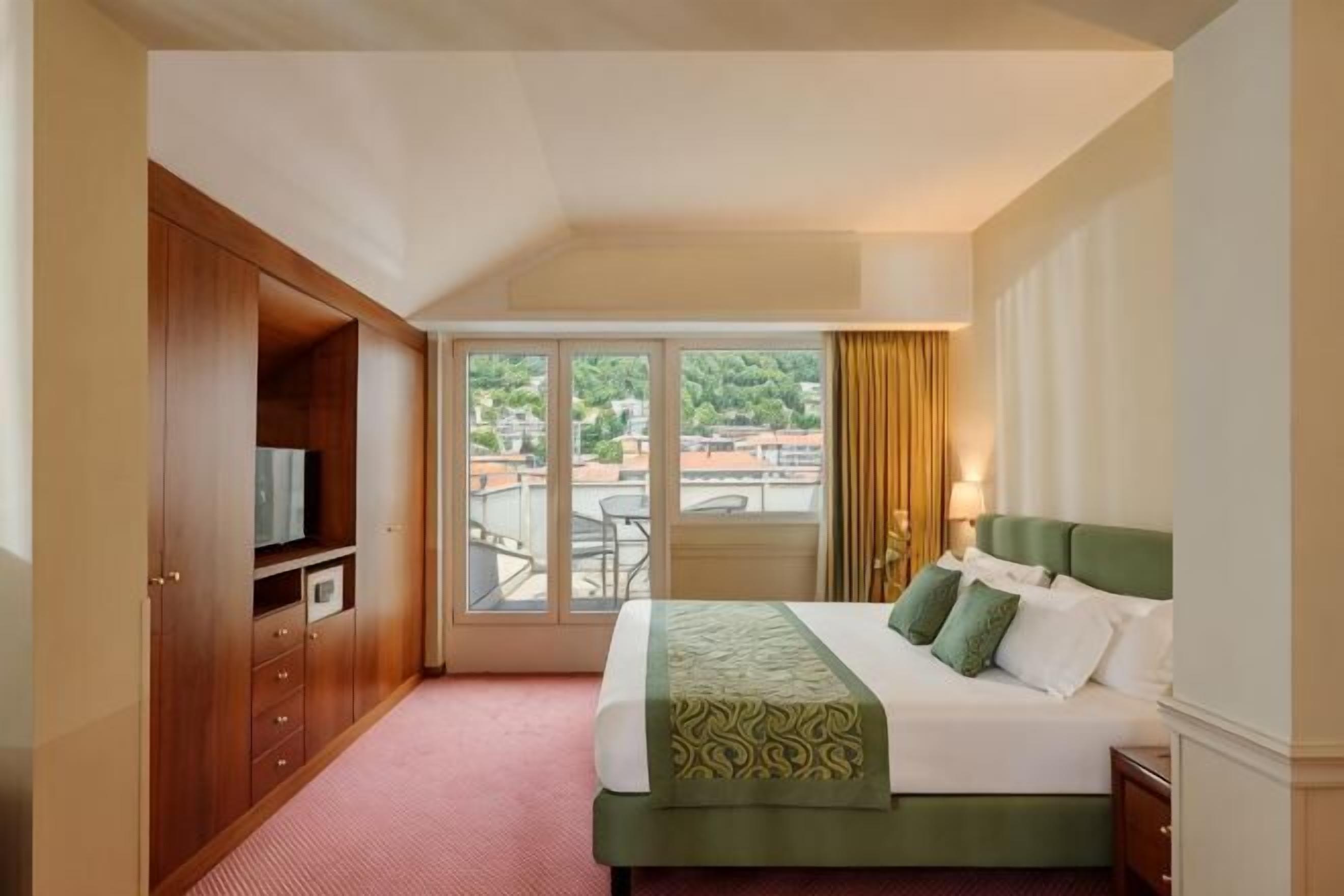 Une chambre d’hôtel avec un lit, une télévision, une armoire et un balcon offrant une vue.